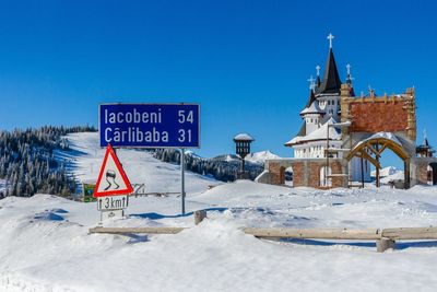 Road sign by snow against clear sky