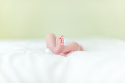 Low section of baby lying on bed