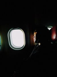 Side view of man looking through airplane window