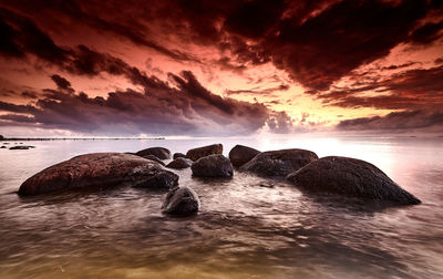 Rocks on sea against sky during sunset