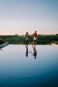 Couple standing by swimming pool in lake against sky