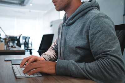 Midsection of man using computer on desk in office