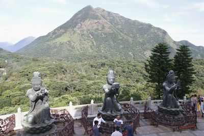 Statue against trees and mountains against sky