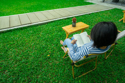 Rear view of woman sitting on grass