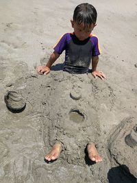 High angle view of boy playing on sand at beach