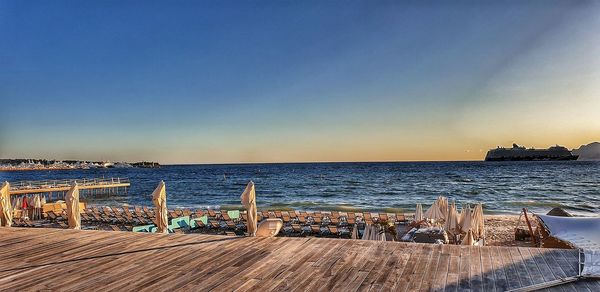 Wooden posts on beach against sky during sunset