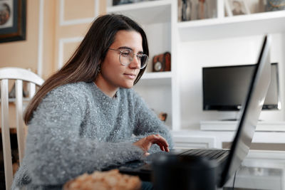 Young woman using mobile phone while sitting on table