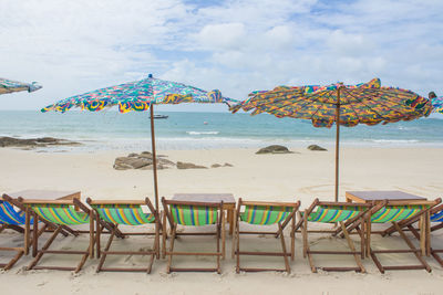 Chairs and parasols on beach against sky