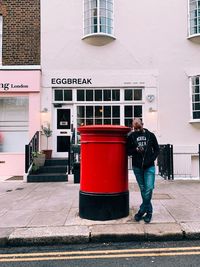 Rear view of man standing on footpath against building