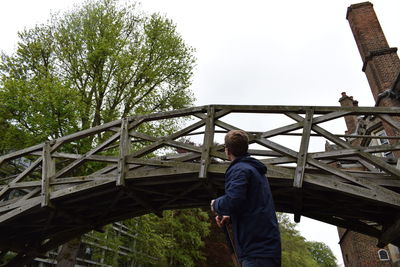 Rear view of man walking on bridge against clear sky