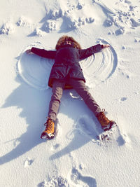 High angle view of woman making snow angel on land