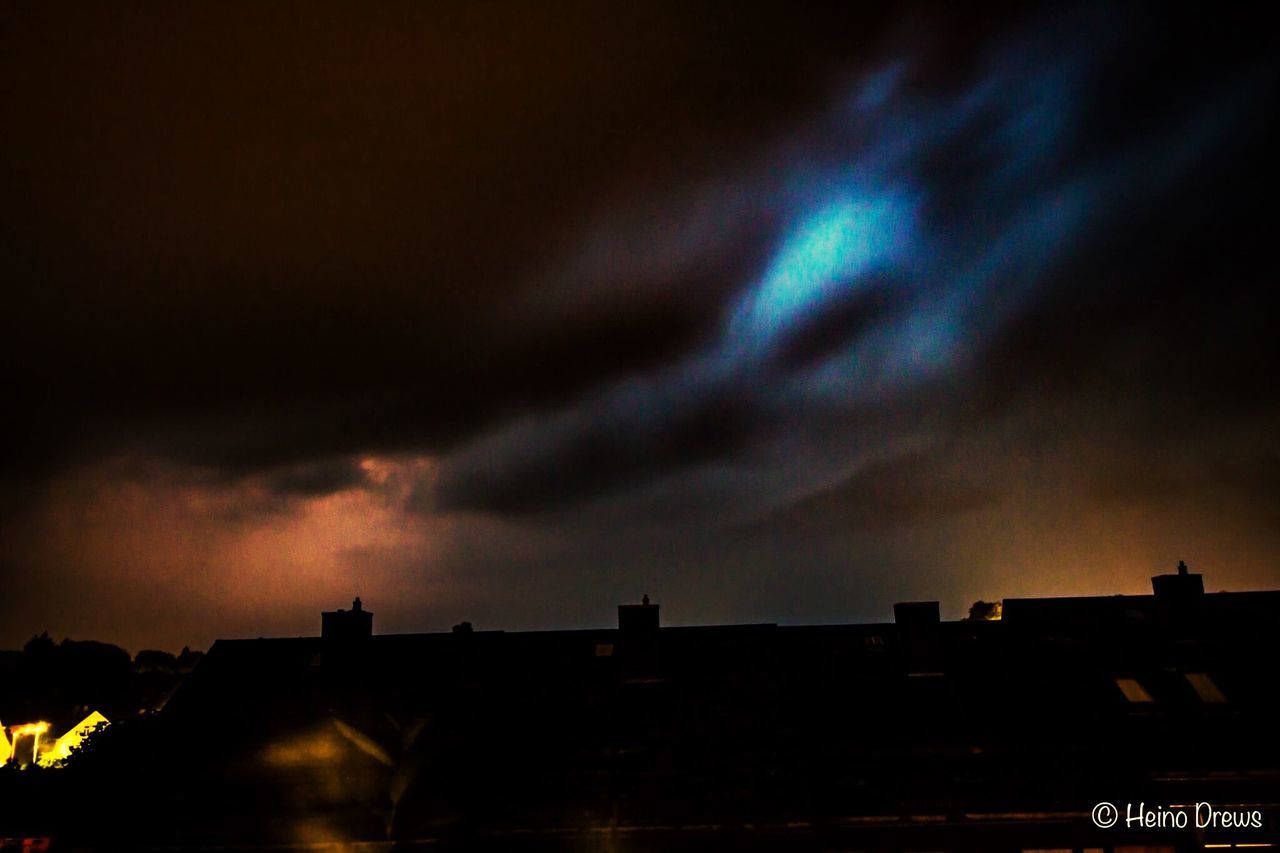 sky, built structure, architecture, night, illuminated, low angle view, cloud - sky, dramatic sky, storm cloud, cloudy, weather, city, building, outdoors, overcast, dark, no people, cloud, nature, beauty in nature, high section, scenics, multi colored