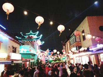 Crowd on illuminated city street against sky at night