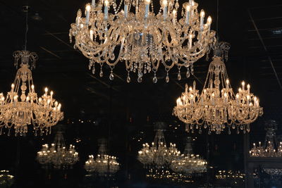 Low angle view of illuminated chandeliers hanging on ceiling in darkroom