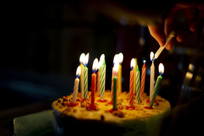 Hand lighting the candles on a cake.