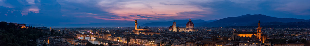 Panoramic view of illuminated buildings in city at sunset