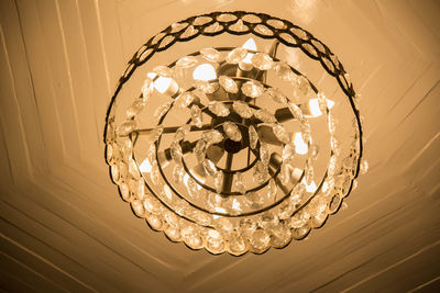 Low angle view of illuminated light bulb hanging from ceiling