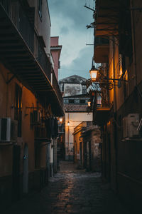 Alley amidst buildings in city at dusk