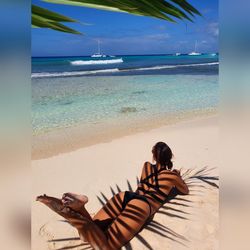 Woman resting at beach against sky