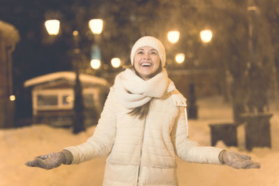 Woman standing on snow in city at night