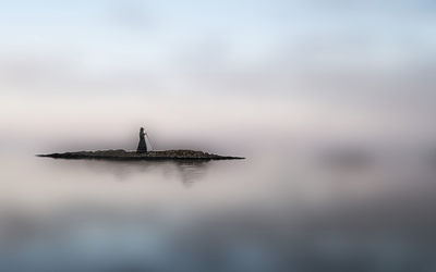 Silhouette sailboat in sea against sky