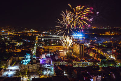 Firework display over illuminated buildings in city at night