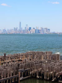 Sea by buildings in city against sky