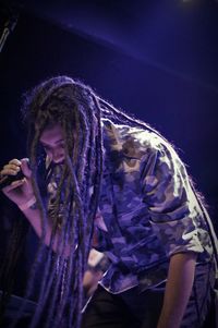 Low angle view of young man with dreadlocks singing on stage