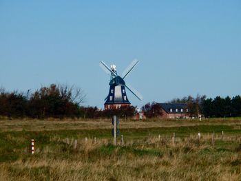 Traditional windmill on field against clear sky