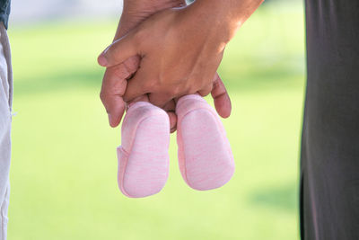 Midsection of couple holding hands and baby booties