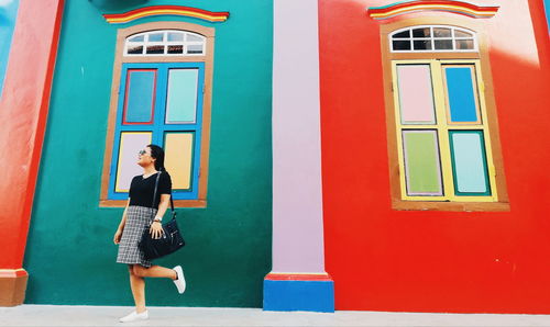 Woman posing against colorful house