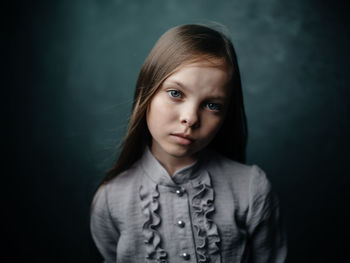 Portrait of cute girl standing against black background