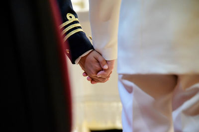 Midsection of men in uniform holding hands