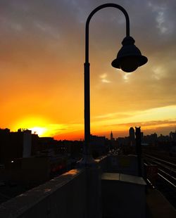 Street light against cloudy sky at sunset