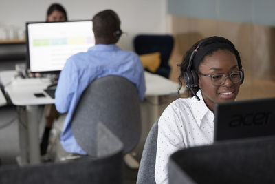 Mid adult woman using headset while sitting in office