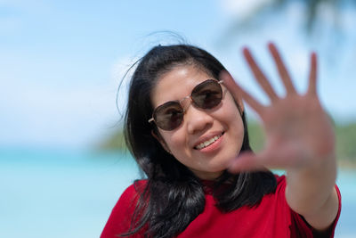 Portrait of young woman wearing sunglasses against sky