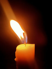 Close-up of lit candle in darkroom