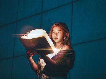 Portrait of a beautiful young woman holding illuminated lamp