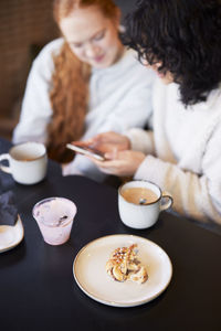 Young women using phone and looking at social media in cafe