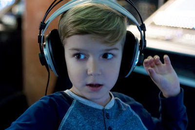 Close-up of thoughtful boy listening to music through headphones in studio