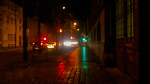 Illuminated street amidst buildings at night