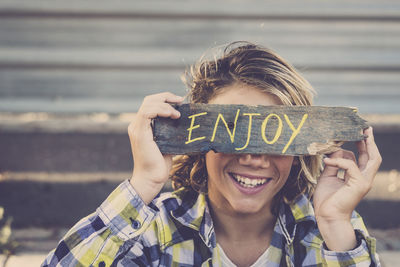 Smiling boy holding text on wood