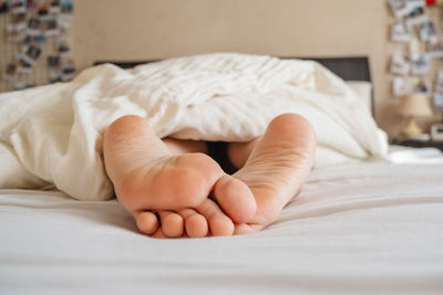 Low section of person lying on bed at home