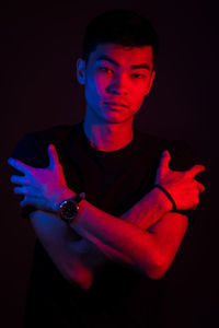 Portrait of young man standing against black background