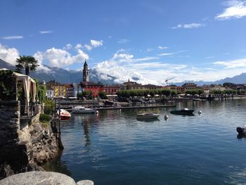 Boats in river by buildings in city against sky