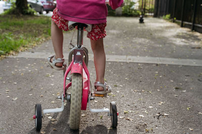 Closeup of girls' feet with white sandals on a pink bike