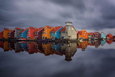 Reflection of multi colored houses in lake against cloudy sky