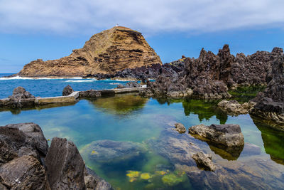 Rock formations by sea against sky