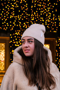 Young woman looking away while standing against christmas decoration