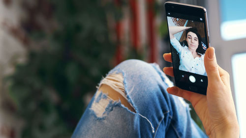 Young woman, girl, brunette, in white shirt and jeans, lying on a sofa, small couch, with smartphone